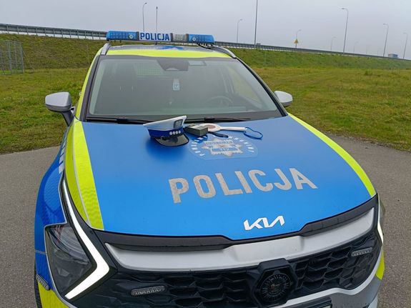 Radiowóz policyjny a na nim położony alco sensor i czapka policyjna
