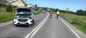 Miejsce zdarzenia drogowego, gdzie kierujący mazdą , na łuku drogi zjechał na przeciwny pas ruchu i zderzył się z ciężarową scanią. Na zdjęciu widoczny uszkodzony pojazd mazda, a w oddali pojazd ciężarowy.