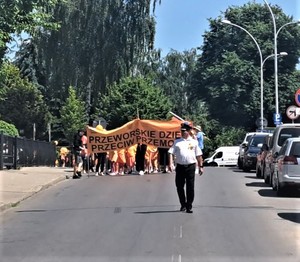 Dzieci podczas marszu przeciwko przemocy trzymają w dłoni pomarańczowe baloniki