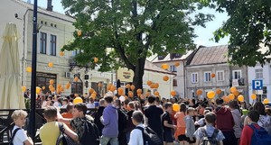 Dzieci podczas marszu przeciwko przemocy trzymają w dłoni pomarańczowe baloniki