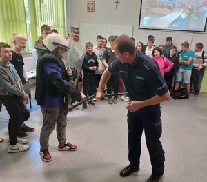 Policjant opisuje zawód policjanta i pokazuje umundurowanie służbowe