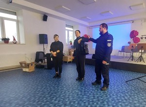 Funkcjonariusz zaprosił na środek osobę opiekująca się seniorami również  z torebką i pokazał jak nie dać sobie ukraść z torebki wartościowych przedmiotów ii w jaki sposób złodziej to robi