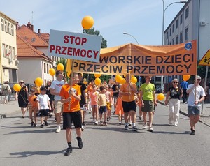 Przemarsz dzieci z pomarańczowymi balonikami ulicami miasta Przeworsk