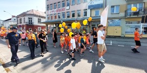 Przemarsz dzieci z pomarańczowymi balonikami ulicami miasta Przeworsk