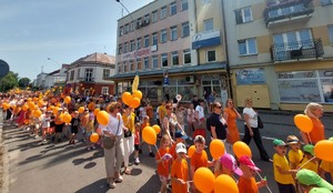 Przemarsz dzieci z pomarańczowymi balonikami ulicami miasta Przeworsk