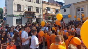 Przemarsz dzieci z pomarańczowymi balonikami ulicami miasta Przeworsk