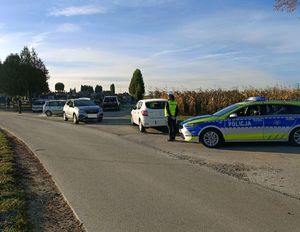 Policjant stoi koło radiowozu podczas prowadzonych działań