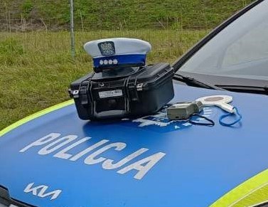 Radiowóz a na nim położona czapka policyjna i alcosensor