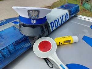Na samochodzie policyjnym lezy czapka policjanta ruchu drogowego i alco sensor