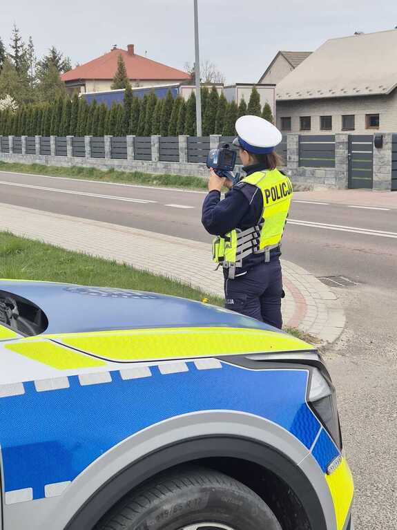 Policjantka przeworskiej drogówki, stojąca obok radiowozu, mierzy prędkość.