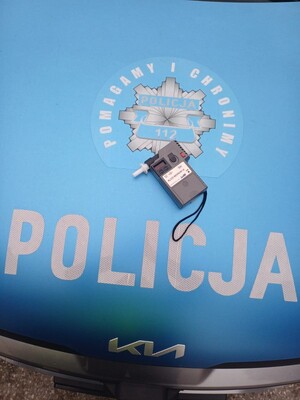 Alcosensor na tle radiowozu i napisu POLICJA