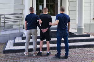 Policjanci prowadzą zatrzymanego mężczyznę